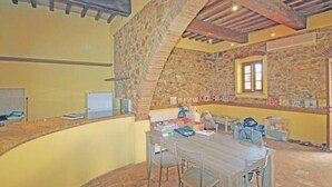 Una cocina rústica con pared de piedra, una mesa de madera y una ventana.