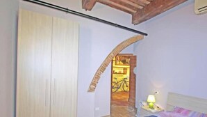 Un dormitorio con cama, mesita de noche, lámpara y armario.