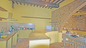 Una cocina con pared de piedra, techo de madera y encimera curva.