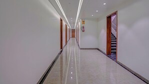 A long, well-lit corridor with a polished floor, wooden doors, and a staircase on the right. - Townhouse Skyboat XLO Point (Nashik)