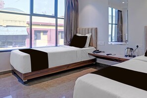 Ett modernt hotellrum med ett stort fönster, en säng, ett sängbord och en spegel.
