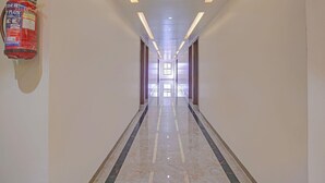 A corridor with a fire extinguisher mounted on the wall, recessed lighting, and a reflective floor. - Townhouse Skyboat XLO Point (Nashik)