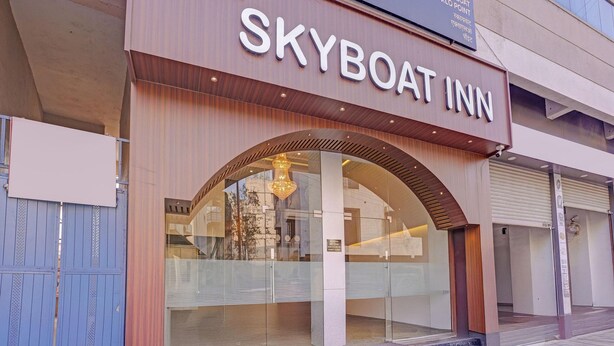 A hotel named Skyboat Inn with a modern facade, large glass windows, and a prominent arched entrance. - Townhouse Skyboat XLO Point (Nashik)