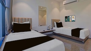 A hotel room with two beds, a desk, a mirror, and artwork on the wall. - Townhouse Skyboat XLO Point (Nashik)