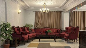 Una sala de estar formal con un conjunto de sofá rojo, una araña y una planta en maceta.