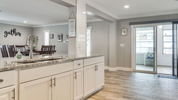A kitchen with a granite countertop, white cabinets, and a backsplash with the word 'gather' on the wall. - Steps to Bayshore Blvd! Snowbird Retreat w/ Pool (Tampa)
