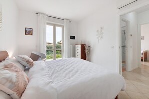 Een slaapkamer met een bed, een dressoir, een radiator en uitzicht op de omgeving.