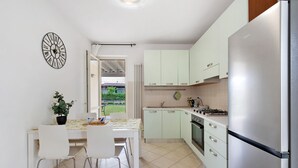Una cocina moderna con armarios blancos, un refrigerador de acero inoxidable y un comedor con mesa y sillas.