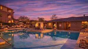 A swimming pool with lounge chairs and umbrellas, surrounded by buildings with balconies. - Indigo-Communal Pool, Hot Tub, Gym & Movie Theater (Scottsdale)