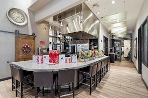 A modern kitchen with a central island, stainless steel appliances, and a wooden door with a wreath. - Indigo-Communal Pool, Hot Tub, Gym & Movie Theater (Scottsdale)