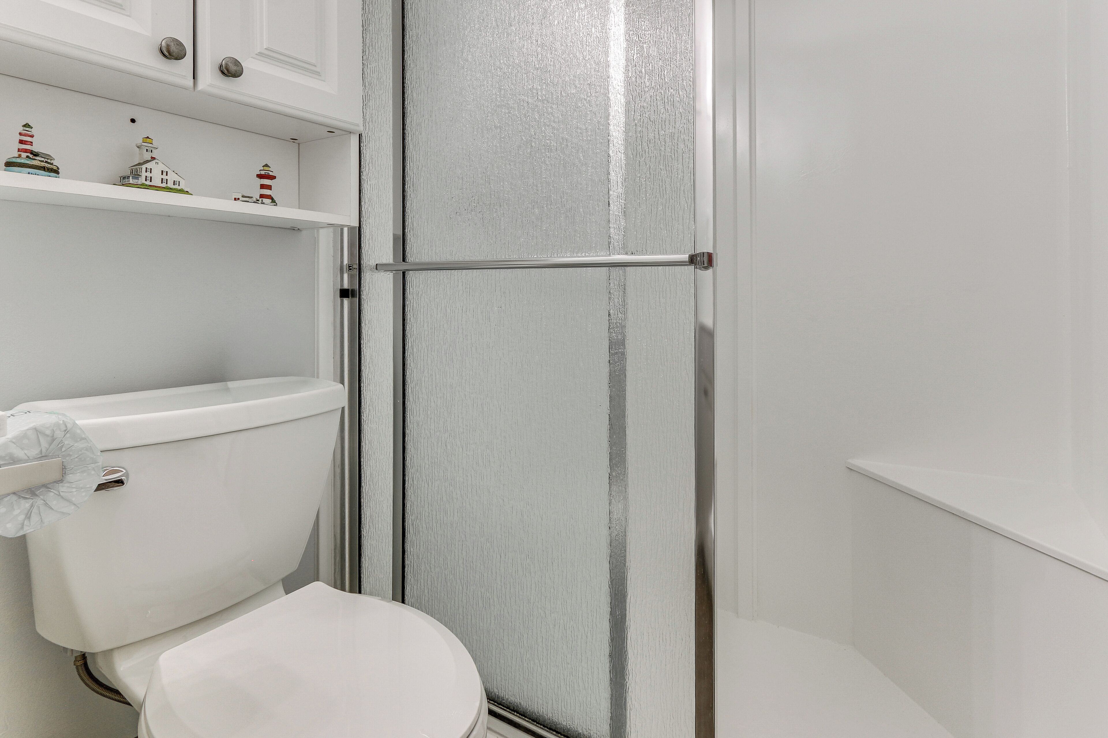 Een badkamer met toilet, douchecabine en een plank met decoratieve objecten.