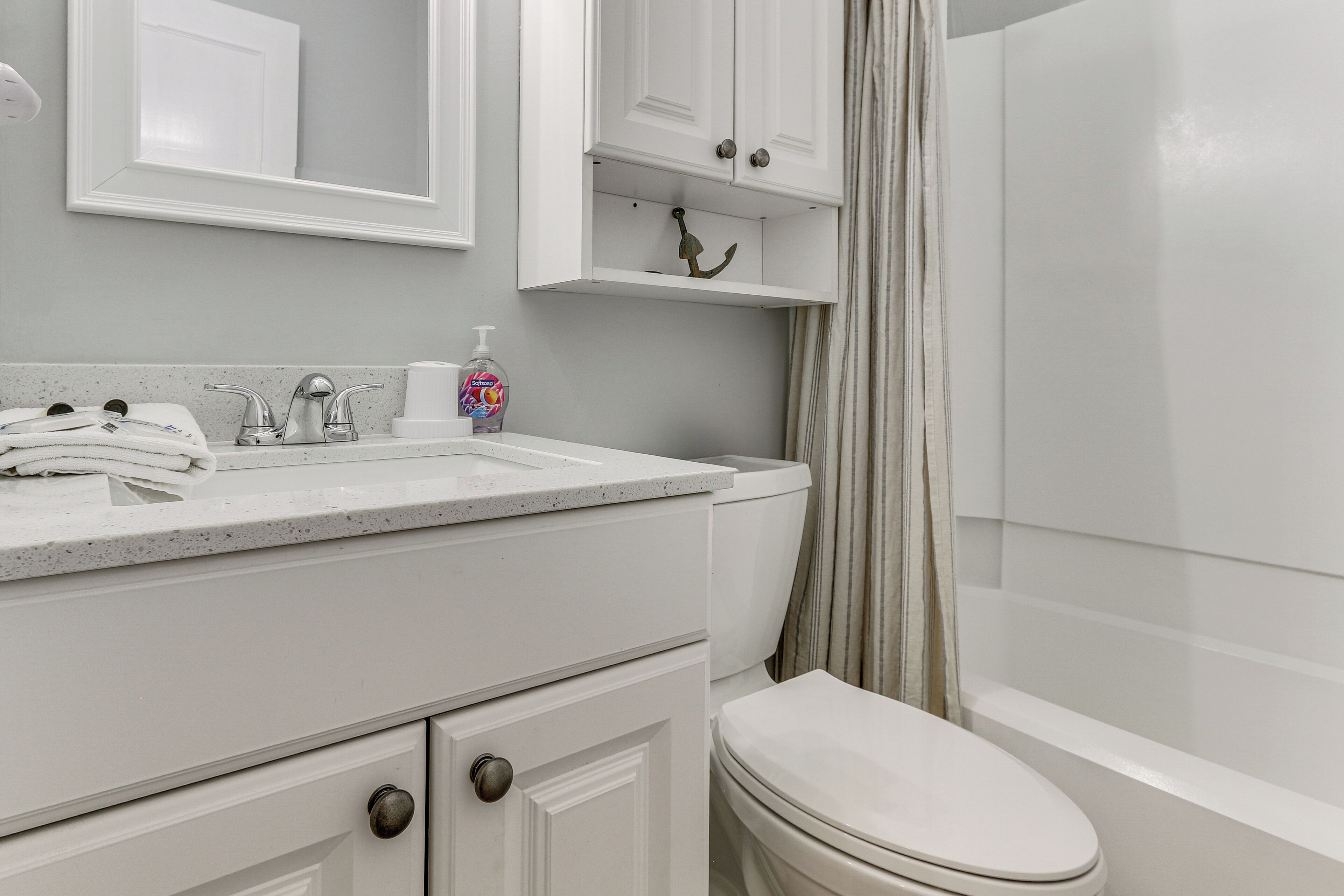 A bathroom with a white sink, a toilet, a shower curtain, and a mirror above the sink.
