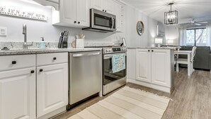 A modern kitchen with white cabinetry, stainless steel appliances, and a granite countertop. - 'folly Tides' HHI Condo w/ Beach, Pools & Tennis! (Hilton Head Island)