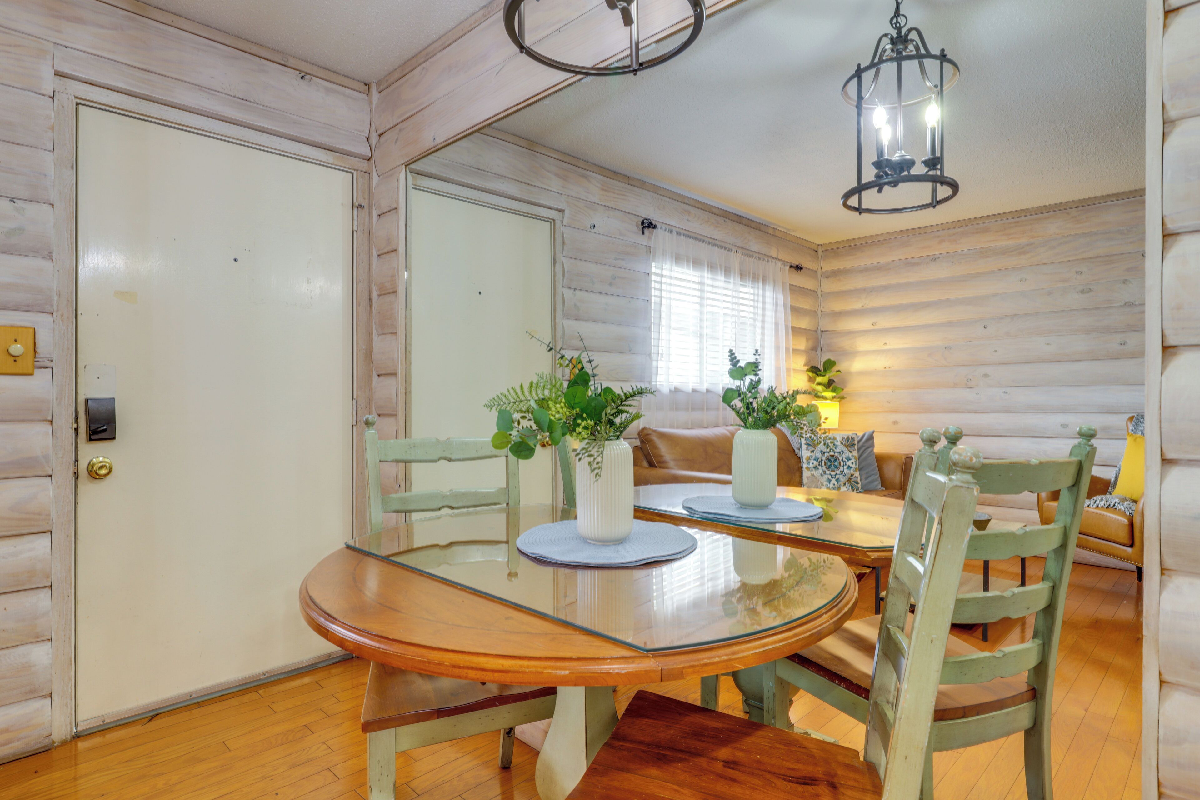 A wooden interior with a dining table, chairs, and a chandelier.