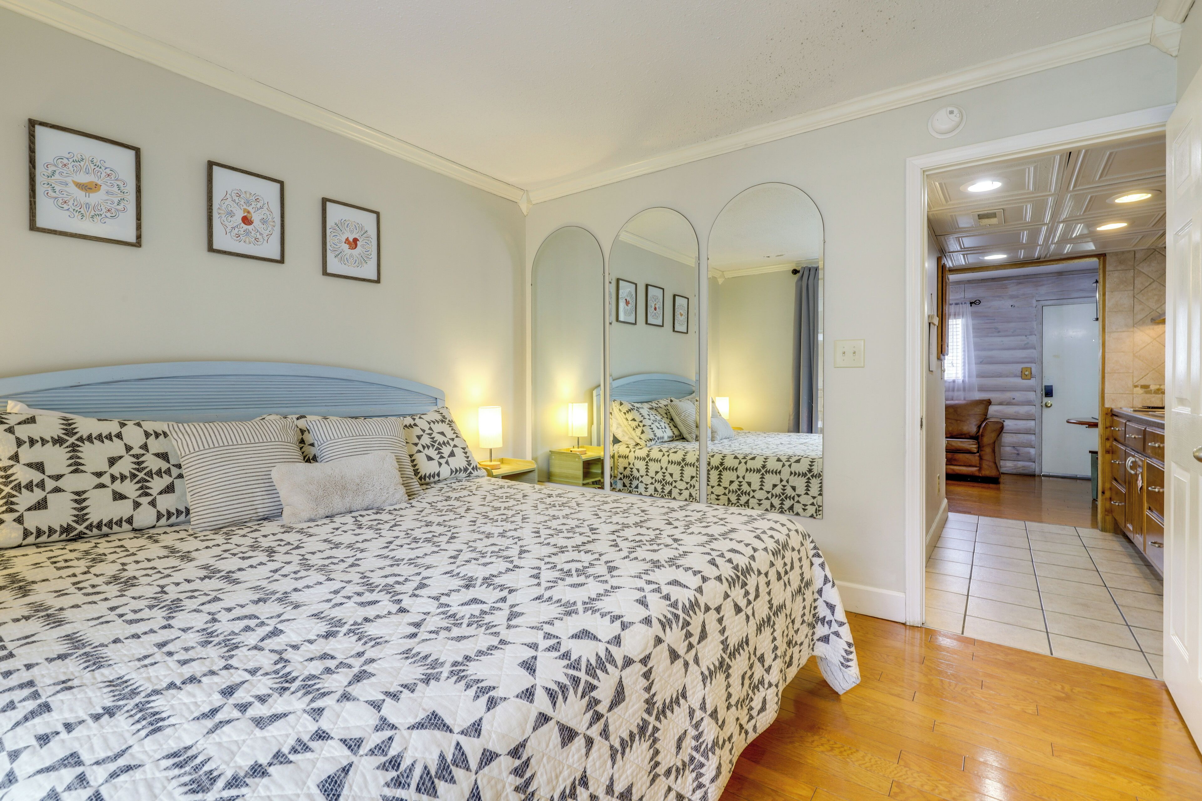 Un dormitorio con una cama grande, mesitas de noche, un espejo y cuadros en la pared.