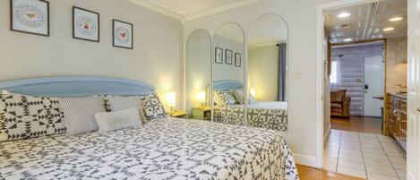 Un dormitorio con una cama grande, mesitas de noche, un espejo y cuadros en la pared.