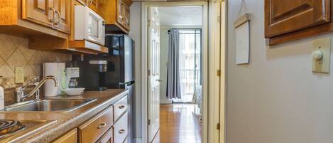 Cocina con armarios de madera, microondas y pileta de acero inoxidable.