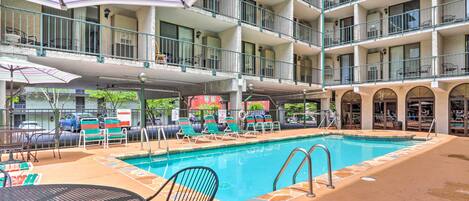 Un hotel de varios niveles con piscina, mobiliario exterior y balcones.