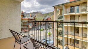 Ein Balkon mit Tisch und Stühlen, der auf einen Parkplatz und Gebäude mit mehreren Etagen und Balkonen blickt.
