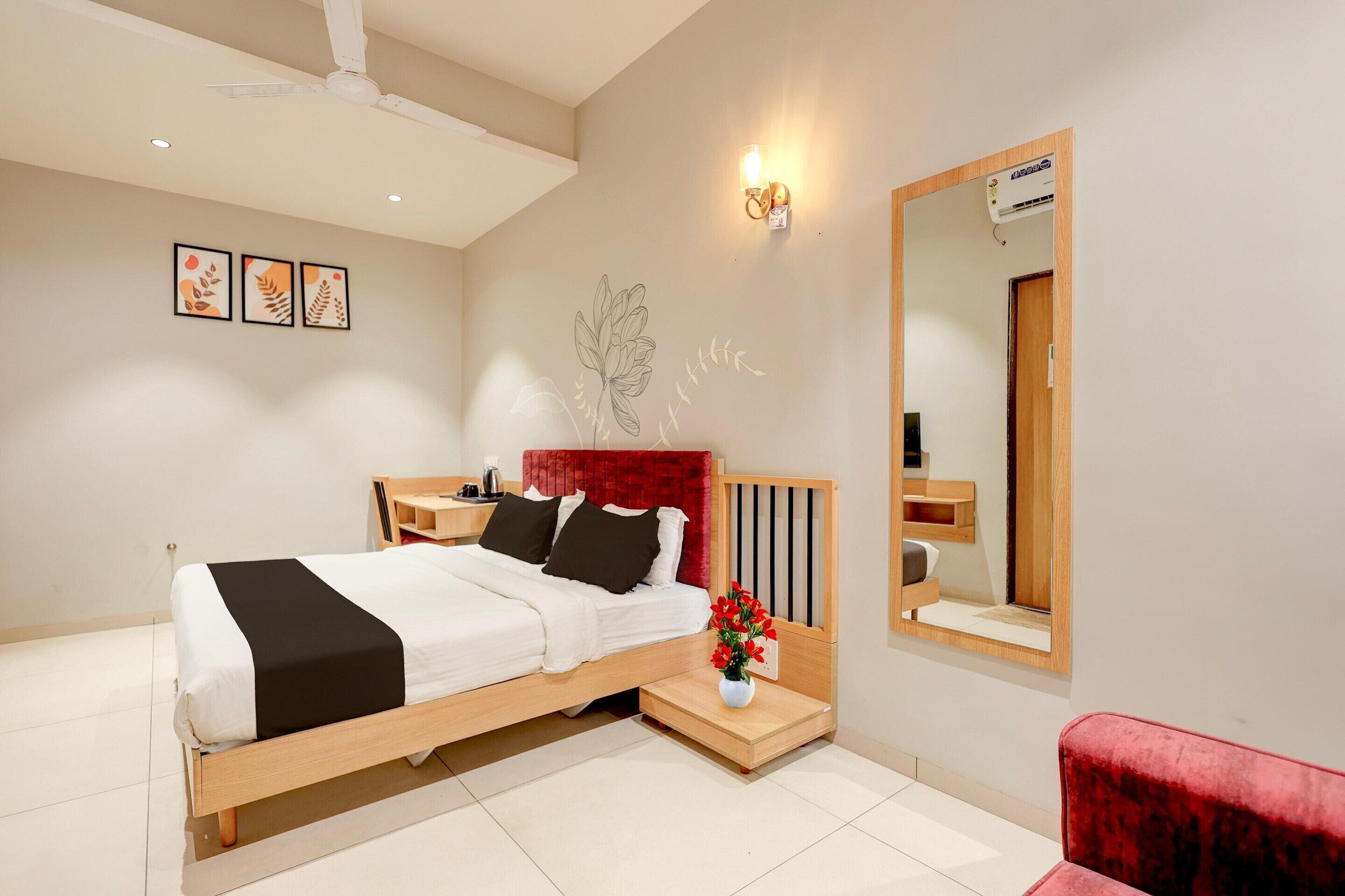Un dormitorio moderno con cama, mesitas de noche, una silla roja, un espejo y decoración en la pared.