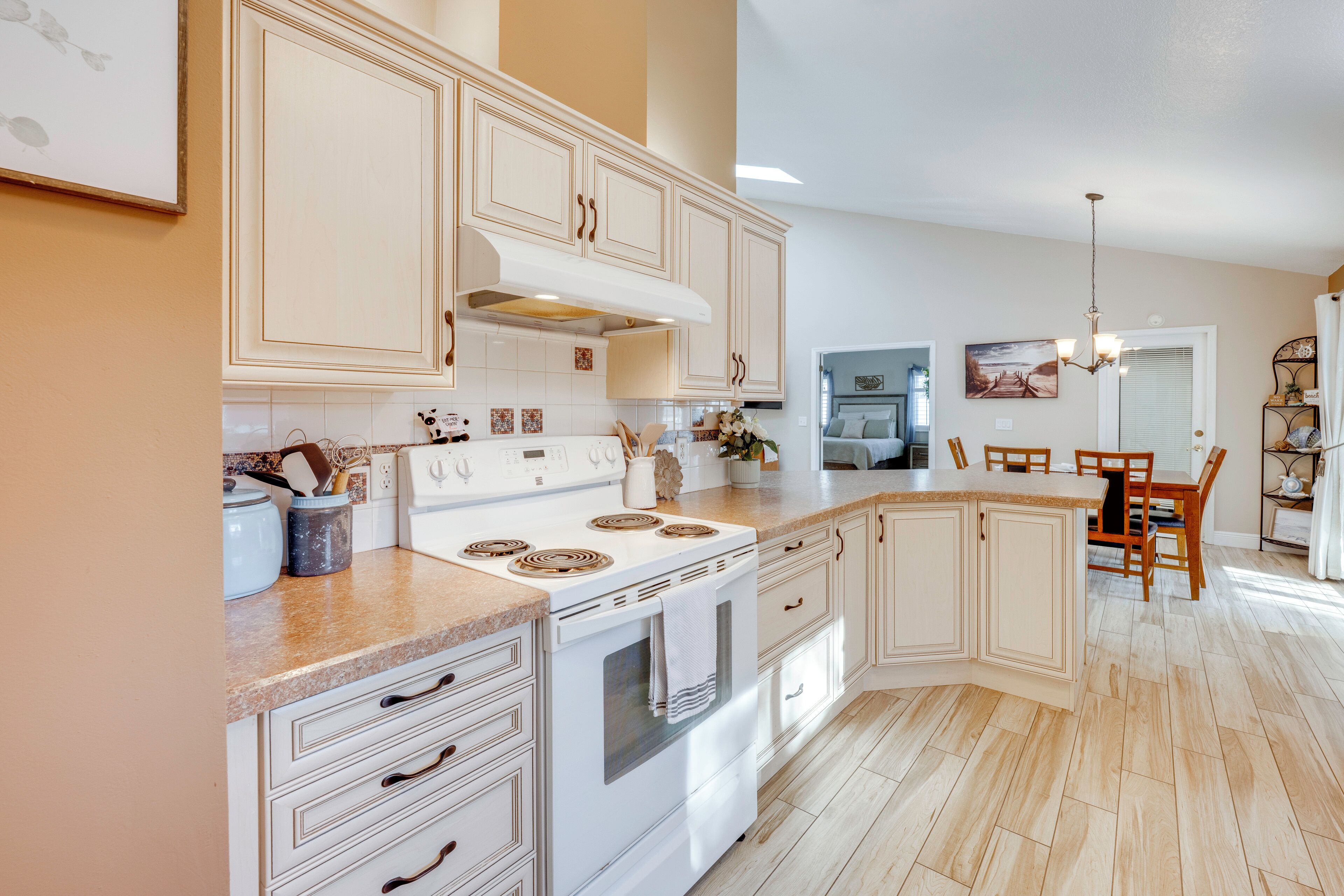 A kitchen with white cabinetry, a stove, and a dining area with a table and chairs.