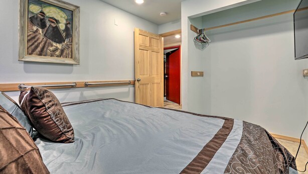 Une chambre à coucher avec un lit, un tableau accroché au mur et une porte donnant sur une autre pièce.