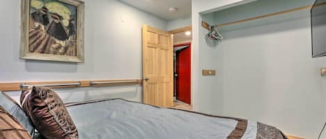Ein Schlafzimmer mit einem Bett, einem Bild an der Wand und einer Tür zu einem anderen Raum.