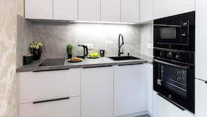 Een moderne keuken met witte kastjes, een zwarte magnetron en een ingebouwde oven.