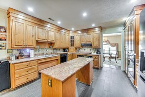 A kitchen with wooden cabinets, granite countertops, and stainless steel appliances.