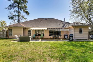 A single-story house with a covered patio, a grill, and outdoor seating.