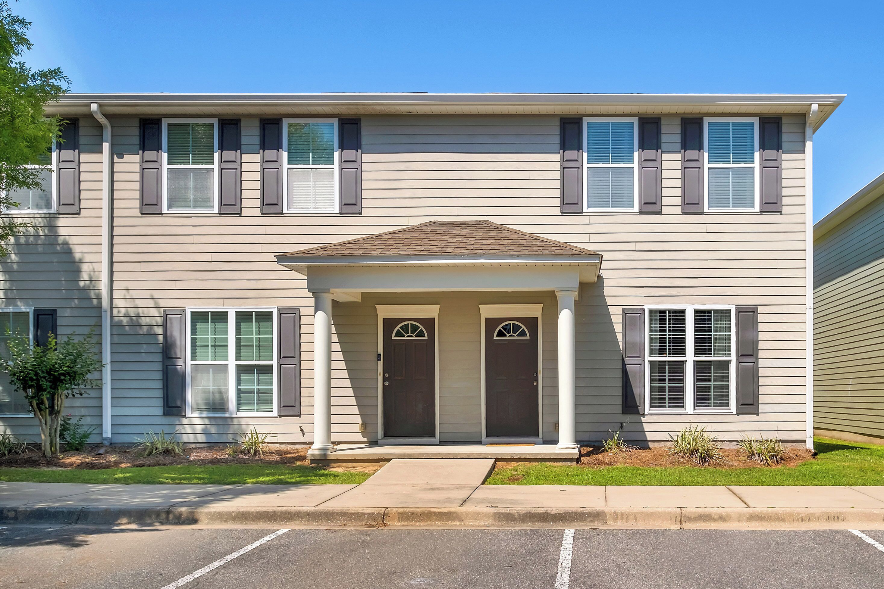A two-story building with a central entrance, two doors, and a small porch.