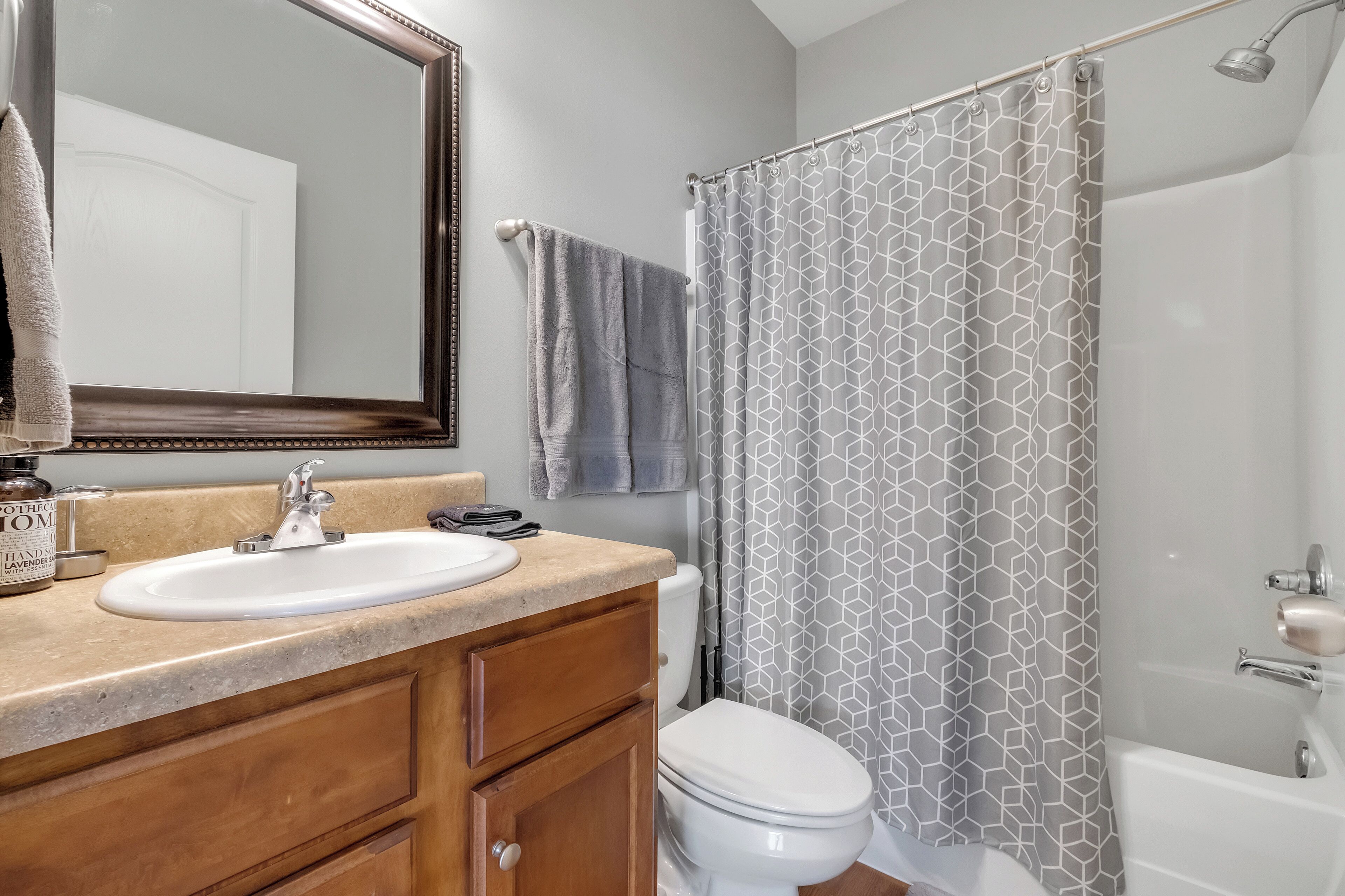 Un bagno con lavandino, specchio, portasciuga, tenda da doccia, water e vasca.