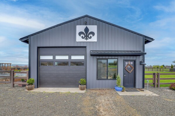 A modern building with a large garage door, a dark entrance door, and a decorative emblem above the door. - Uncork & Unwind: Scenic Walla Walla Escape (Walla Walla)