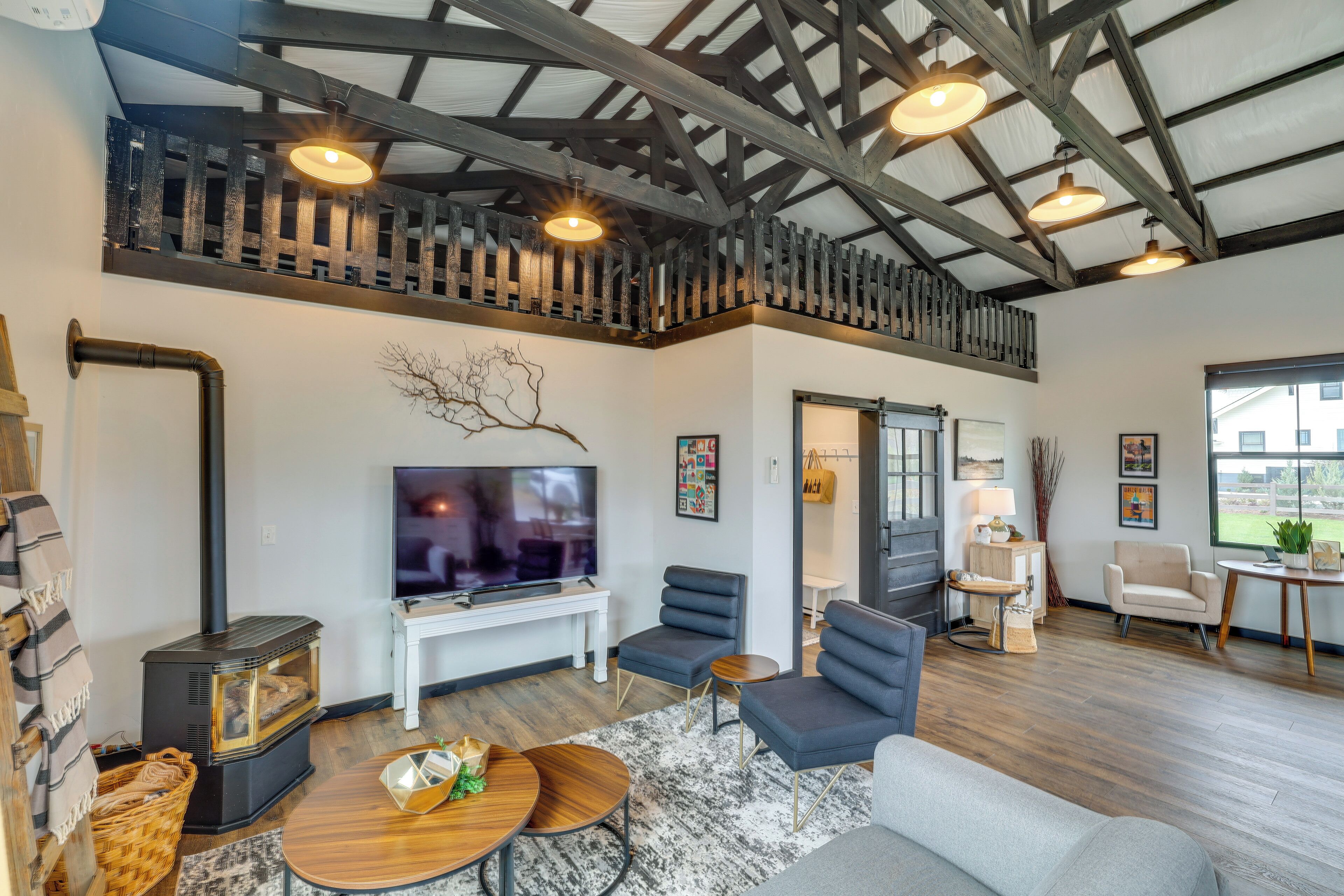 A modern living room with a fireplace, comfortable seating, a television, and a large window.