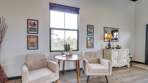 Una habitación con dos sillones, una mesita redonda, un armario y una ventana con vistas.