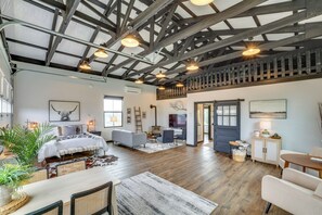 A spacious room with a high ceiling, exposed beams, a bed, a sofa, a dining table, and a staircase. - Uncork & Unwind: Scenic Walla Walla Escape (Walla Walla)