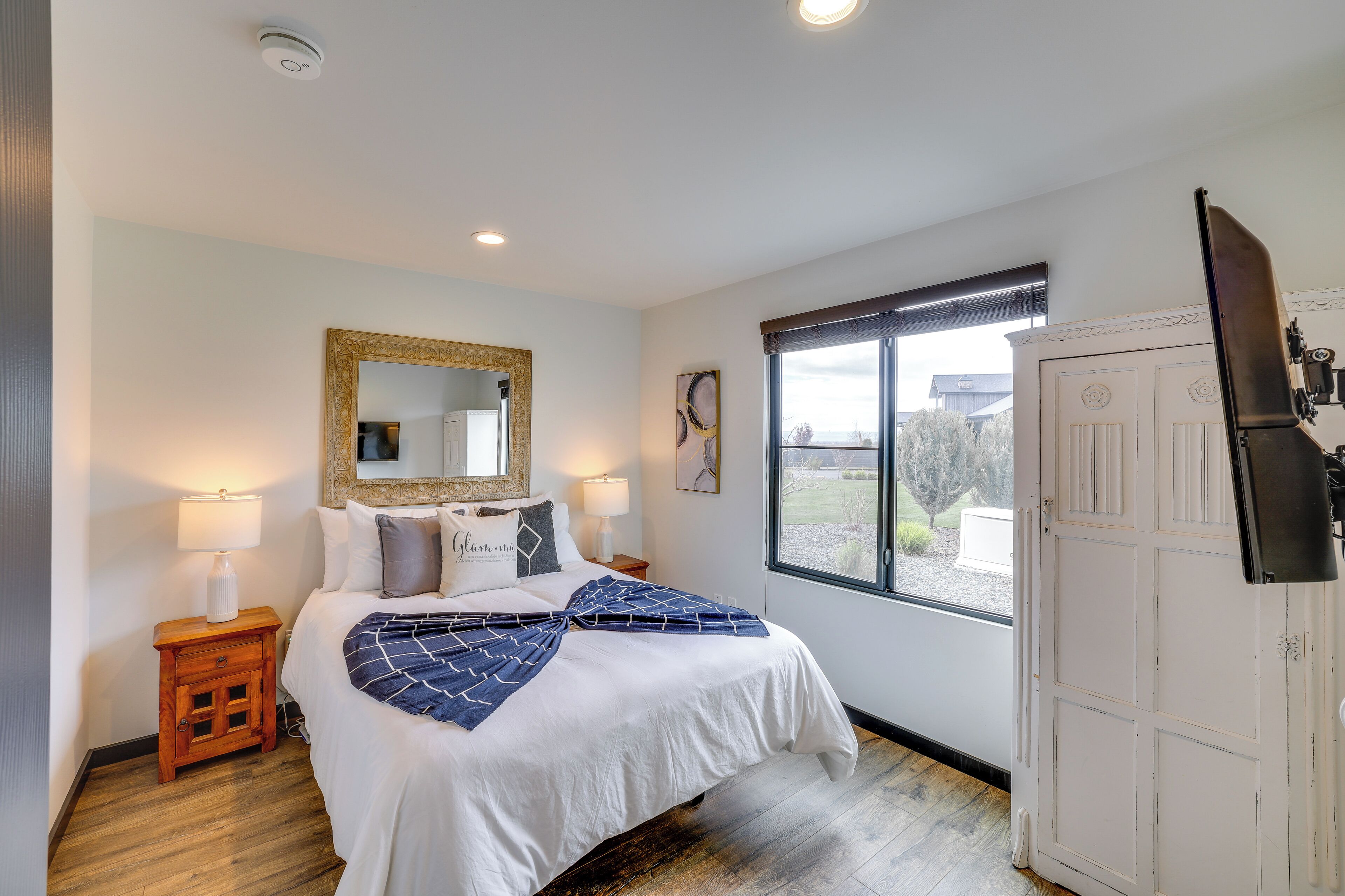 Une chambre à coucher avec un lit, des lampes de chevet, un miroir, une fenêtre et une porte.