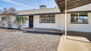 A single-story house with a covered porch, a gravel driveway, and a wreath on the door. - Explore Gila Valley & Eac! Modern Thatcher Home (Thatcher)