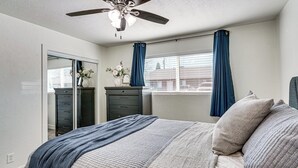 A bedroom with a bed, a dresser, a mirror, and a ceiling fan. - Explore Gila Valley & Eac! Modern Thatcher Home (Thatcher)