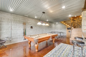 A pool table with cues, a billiards table, and a bar area with stools. - 210-acre Cabin w/ Trails & Hot Tub in Tuscumbia! (Tuscumbia)