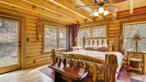 Ein Schlafzimmer in einer Blockhütte mit einem Bett, einer Holzbank und einem Deckenventilator.