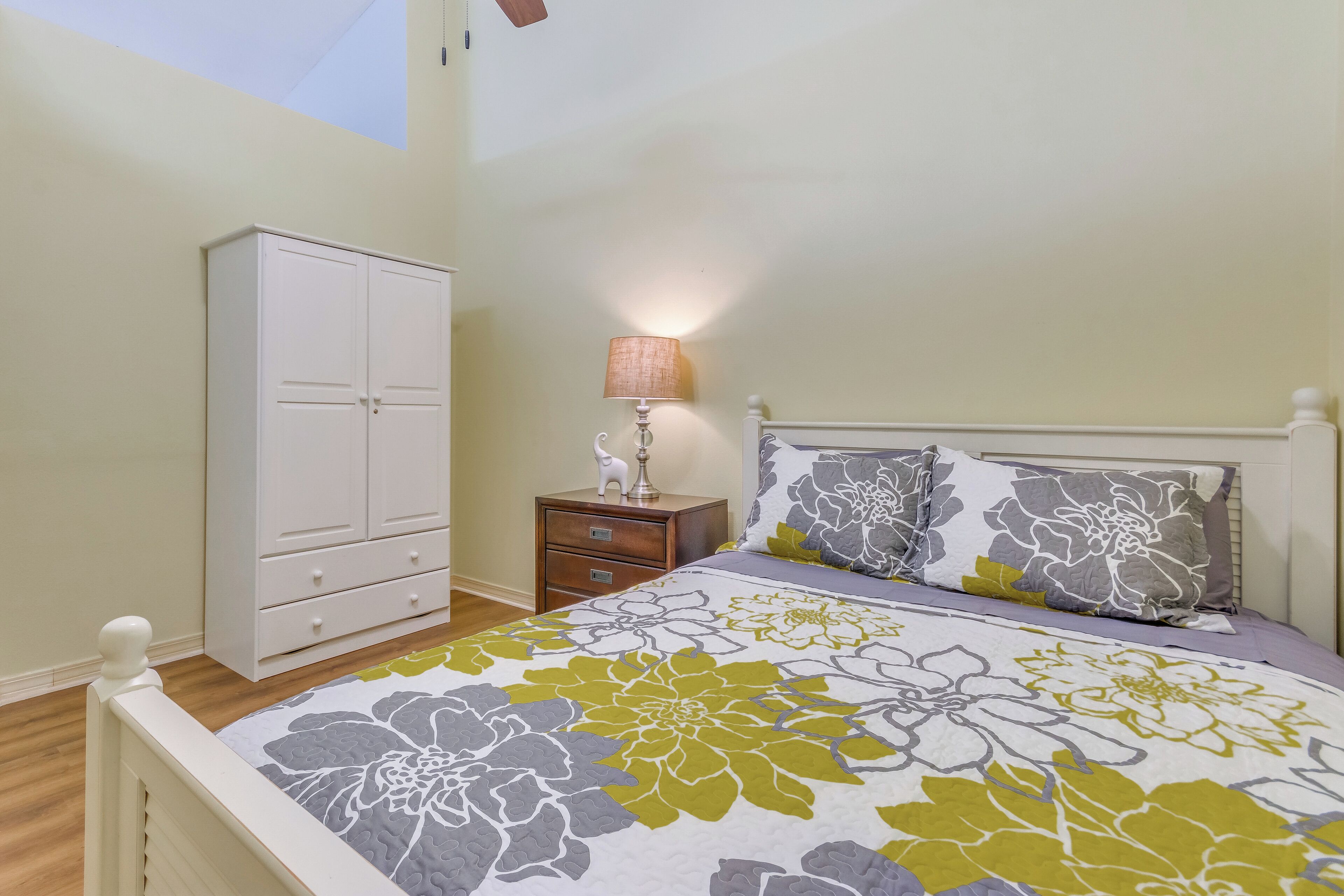 Un dormitorio con cama, mesita de noche, armario y lámpara.