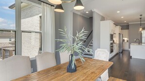 Eine moderne Küche mit weißen Schränken, einem Holztisch und einer Treppe, die in ein Obergeschoss führt.