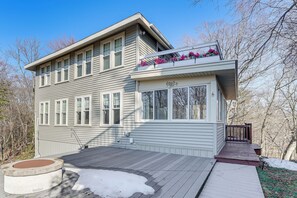 A two-story house with a deck, a covered porch, and a window with a flower box. - Walk to Beach! Serene Lake Michigan Home w/ Deck (Grand Haven)