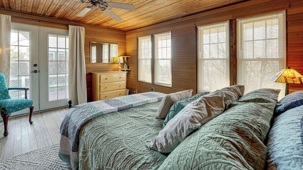A bedroom with a bed, a dresser, a chair, and a ceiling fan. - Walk to Beach! Serene Lake Michigan Home w/ Deck (Grand Haven)
