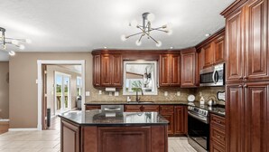 A kitchen with wooden cabinets, a central island, a microwave, and an oven. - Northern Kentucky Gem w/ Yard & In-ground Pool! (California)