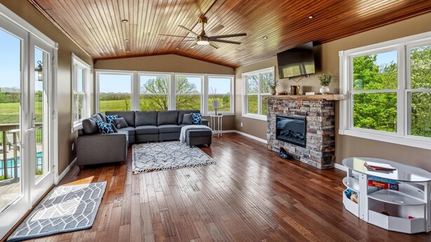 A spacious living room with a wooden ceiling, large windows, a fireplace, and a sectional sofa. - Northern Kentucky Gem w/ Yard & In-ground Pool! (California)