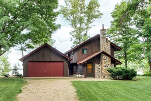 A two-story house with a red garage, a stone chimney, and a well-maintained lawn. - Mille Lacs Lake Cabin: Private Dock, Deck & Grill (Wahkon)