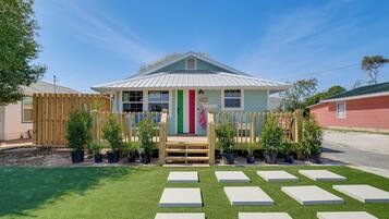 A building with a green roof, a wooden fence, and potted plants.