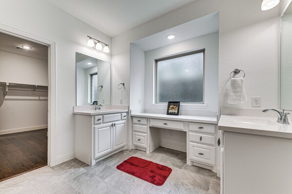 A modern bathroom with white cabinetry, a large mirror, and a red rug. - Near Lake & Family Fun! Spacious Oak Point Home (Little Elm)